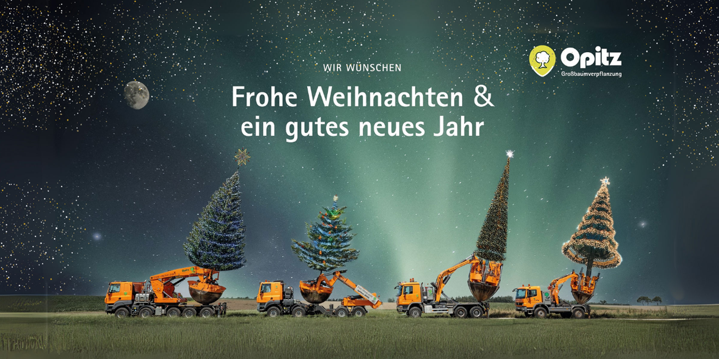 Weihnachtsgruß - Pflanzmaschinen mit Weihnachtsbäumen beladen stehen auf einer Wiese mit Sternenhimmel im Hintergrund